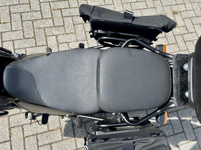 Draufsicht auf einen schwarzen Motorradsitz auf einer mit Ziegeln gepflasterten Oberfläche