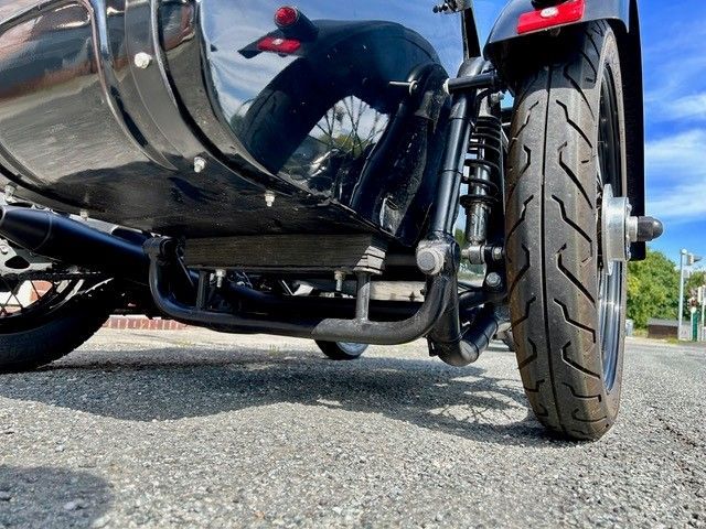 Schwarzes Motorrad mit Beiwagen auf einer Asphaltstraße. Nahaufnahme von unten.