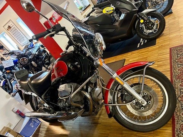 Schwarzes Cruiser-Motorrad mit roten Akzenten, das in einem Ausstellungsraum in einer Halle parkt.