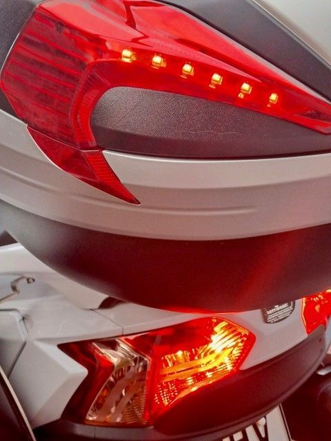 Rot-weiße Rücklichter eines Motorrads, Topcase und Fahrzeugheck.