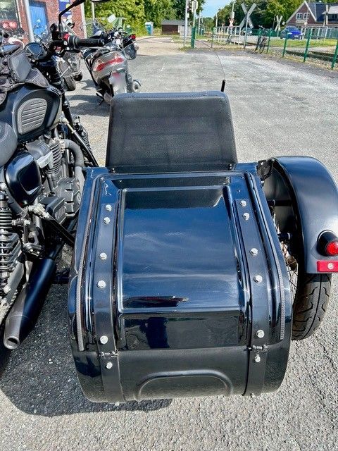 Schwarzer Motorradbeiwagen, der an einem Motorrad befestigt ist und im Freien auf dem Bürgersteig geparkt ist.