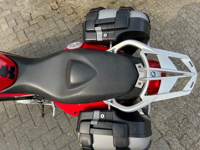 Ein rotes Motorrad mit schwarzem Sitz und schwarzem Gepäck