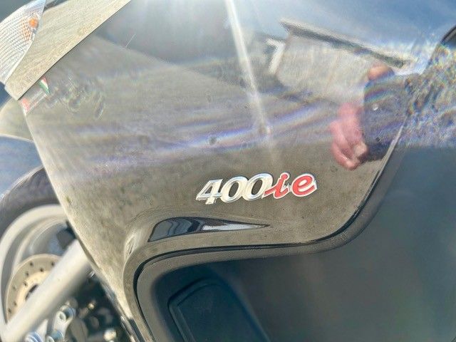 Nahaufnahme einer Motorradverkleidung mit einem 400e-Emblem und einer reflektierenden schwarzen Oberfläche.