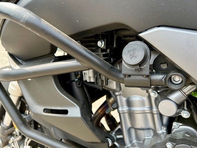 Eine Nahaufnahme eines Motorradmotors mit angeschlossenem Ladegerät.