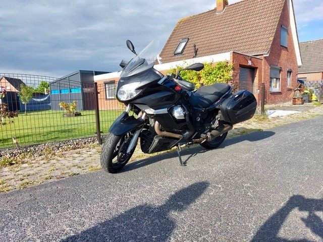 Schwarzes Tourenmotorrad, das auf einer Straße vor einem Haus geparkt ist.