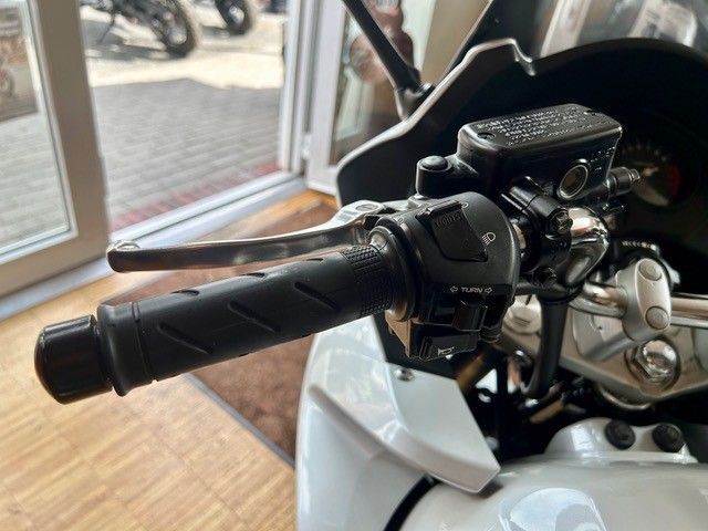Nahaufnahme eines Motorradlenkers und Gasgriffs in einer Werkstatt oder Garage.