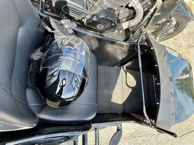 Schwarzer Motorradsitz mit schwarzem Helm in einem Staufach.