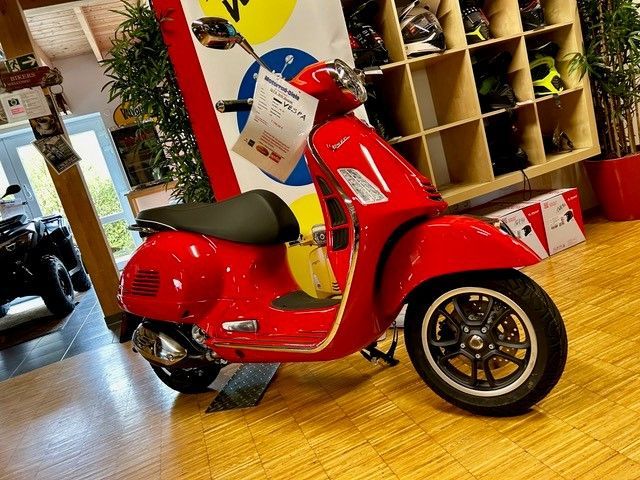 Roter Vespa-Roller in einem Geschäft mit Holzböden und -regalen.