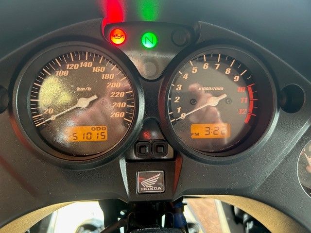 Motorrad-Armaturenbrett mit zwei analogen Anzeigen und leuchtenden roten, grünen und gelben Kontrollleuchten.