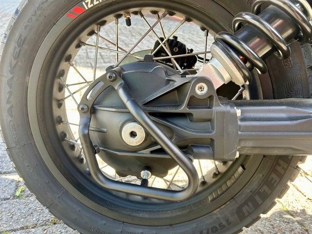 Nahaufnahme eines Motorradhinterrades, Kettenantrieb und silberner Federung.