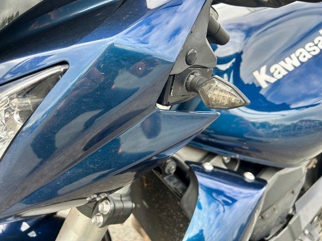 Nahaufnahme einer blauen Kawasaki-Motorradverkleidung und eines Kraftstofftanks mit silbernen Beschlägen