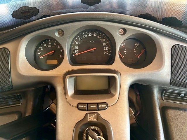 Armaturenbrett eines Motorrads mit Tachometer, Drehzahlmesser, Tankanzeige und Digitalanzeige. Silbernes Finish mit schwarzen Anzeigen und Bedienelementen.