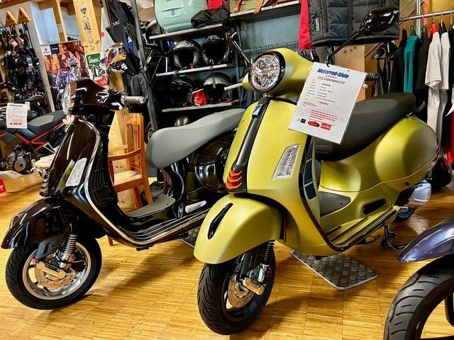 Zwei Vespa-Roller: schwarz und gelb, ausgestellt in einem Geschäft.
