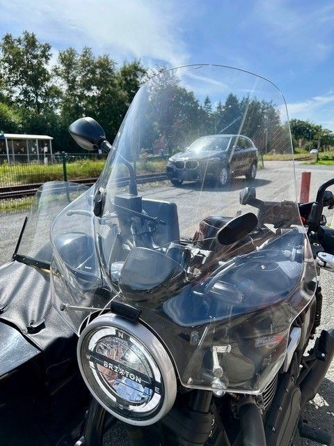 Motorrad mit Windschutzscheibe, Beiwagen und schwarzem Auto im Hintergrund. Sonniger Tag.
