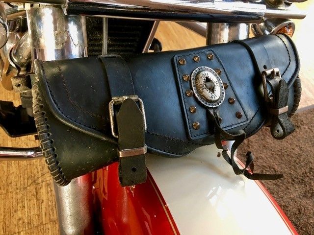 An der Seite eines Motorrads liegt eine schwarze Ledertasche.