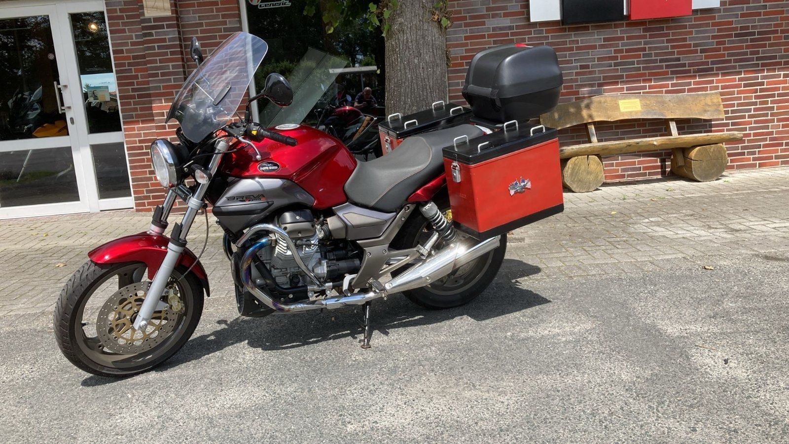 Vor einem Backsteingebäude parkt ein rotes Motorrad.