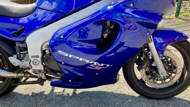 Ein blaues Motorrad ist am Straßenrand geparkt.