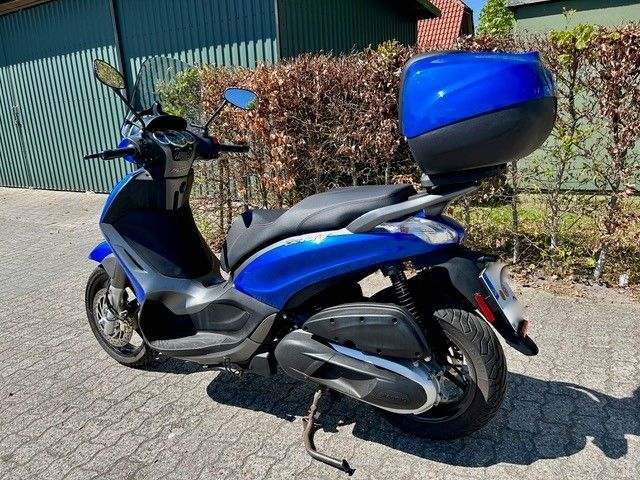 Ein blauer Motorroller steht am Straßenrand.