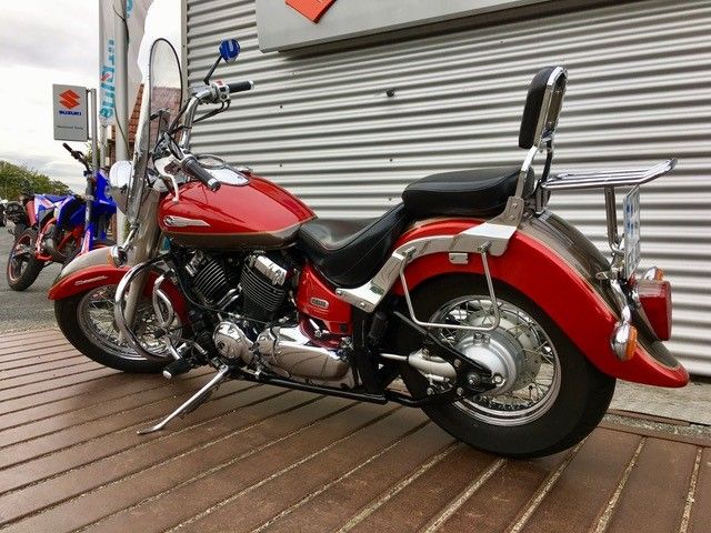 Ein rotes Motorrad ist auf einem Holzdeck vor einem Gebäude geparkt.