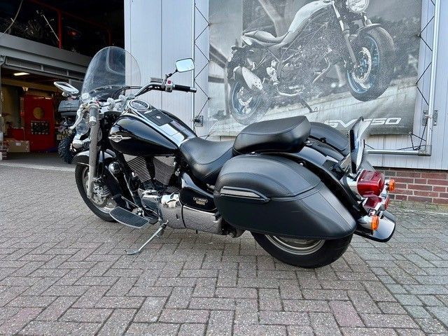 Ein schwarzes Motorrad ist auf einem gepflasterten Gehweg vor einem Gebäude geparkt.