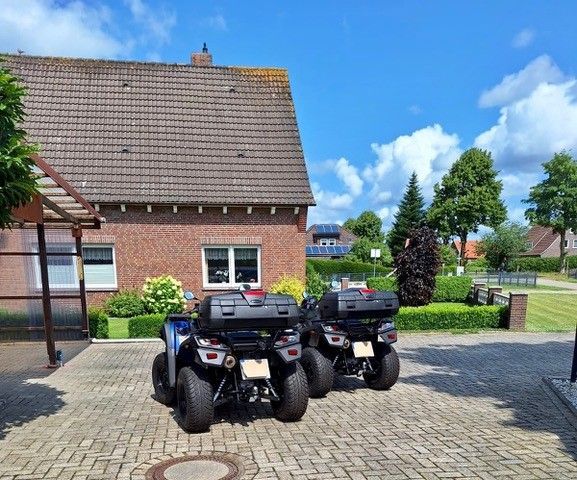 An einem sonnigen Tag parkten zwei Geländefahrzeuge auf einer gepflasterten Auffahrt vor einem gepflasterten Haus.