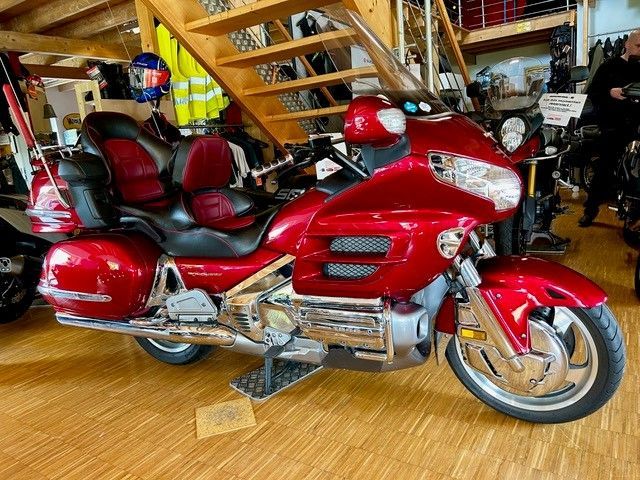 Rotes Honda Gold Wing-Motorrad, drinnen in der Nähe einer Holztreppe geparkt.
