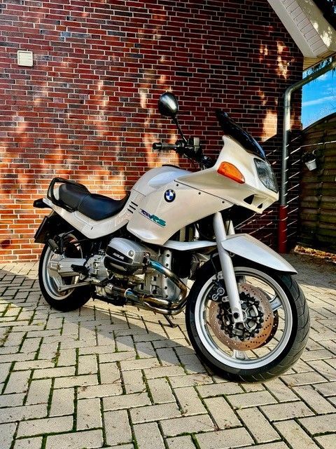 Ein weißes Motorrad steht vor einem Backsteingebäude