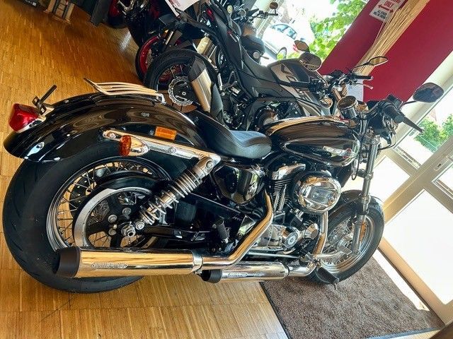 Ein schwarzes Cruiser-Motorrad steht in einem Ausstellungsraum, im Hintergrund sind weitere Motorräder zu sehen.