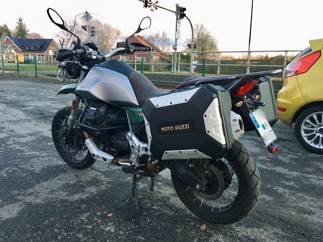 Ein Moto Guzzi Motorrad ist neben einem gelben Auto geparkt