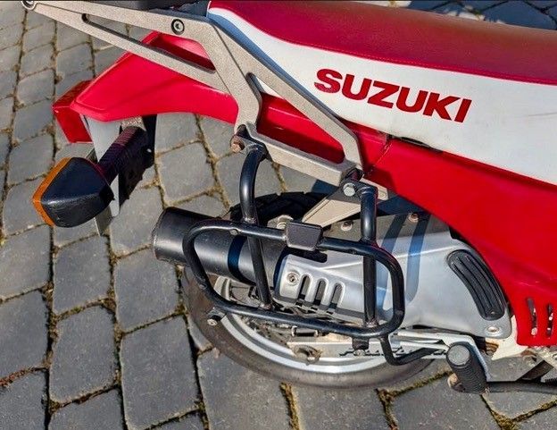 Ein rot-weißes Suzuki-Motorrad ist auf einem gemauerten Bürgersteig geparkt