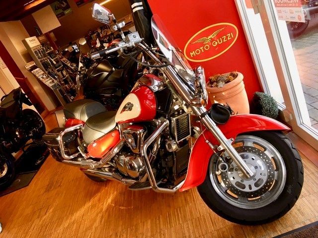 Ein rotes Motorrad steht vor einem roten Schild mit der Aufschrift „Moto Guzzi“