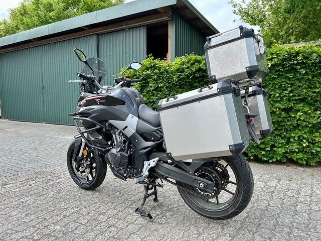 Vor einer Garage steht ein Motorrad mit Gepäck.