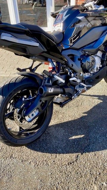 Schwarzes Sportmotorrad mit LV-Auspuff auf dem Bürgersteig.