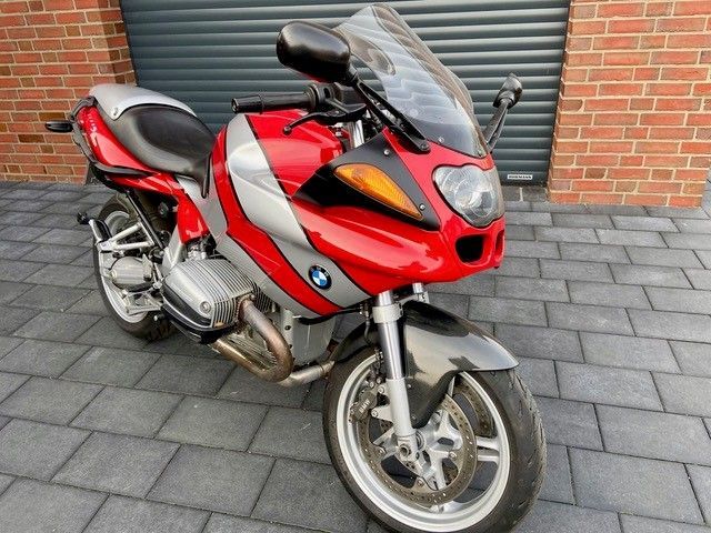 Ein rotes BMW-Motorrad steht vor einem Backsteingebäude