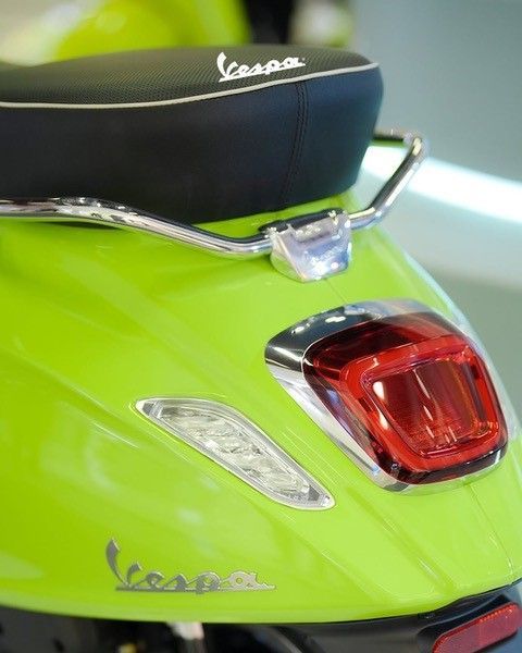 Limettengrüner Vespa-Roller mit schwarzem Sitz, Chrom-Akzenten und rotem Rücklicht.