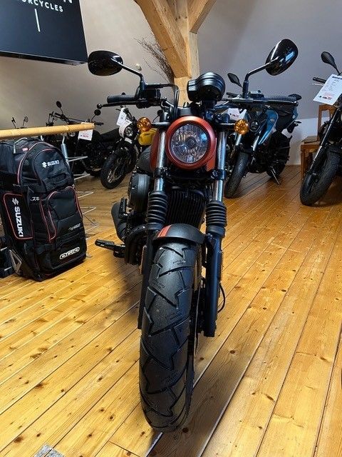 In einem Ausstellungsraum ist ein Motorrad auf einem Holzboden geparkt.