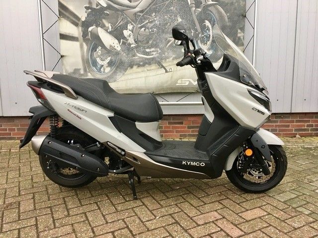 Ein weißer Motorroller ist vor einem Backsteingebäude geparkt.