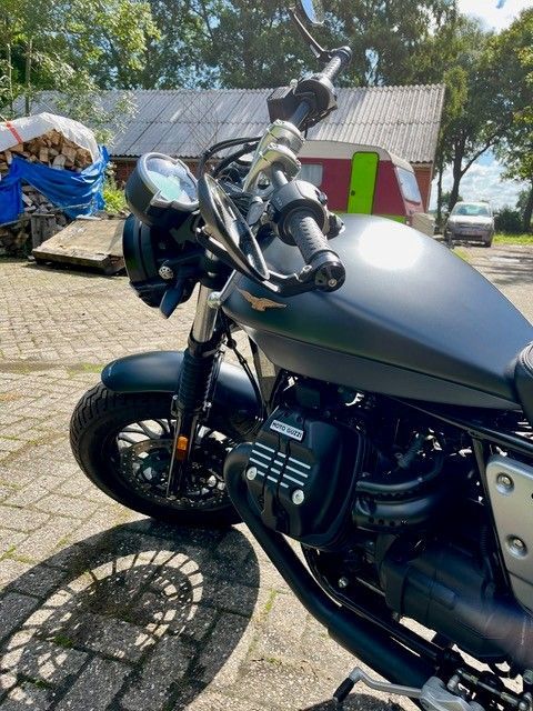 Schwarzes Moto Guzzi-Motorrad, das an einem sonnigen Tag draußen geparkt ist.