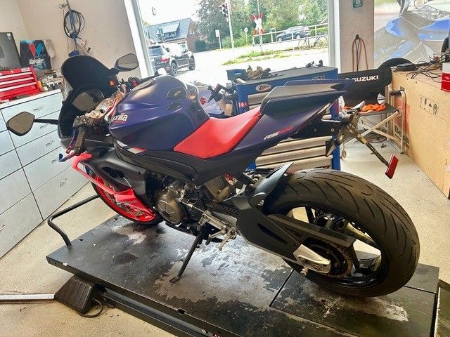 Blaues und rotes Sportmotorrad auf einer Hebebühne in einer Garage