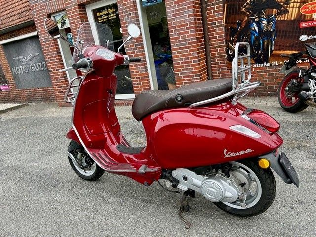 Ein roter Motorroller ist vor einem Backsteingebäude geparkt.