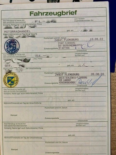 Deutsche Fahrzeugzulassungsbescheinigung mit Stempeln und handschriftlichen Anmerkungen auf weißem Papier