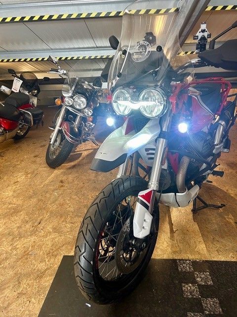 Drei Sportmotorräder sind drinnen geparkt, das vordere weiße Motorrad hat eingeschaltete Scheinwerfer.