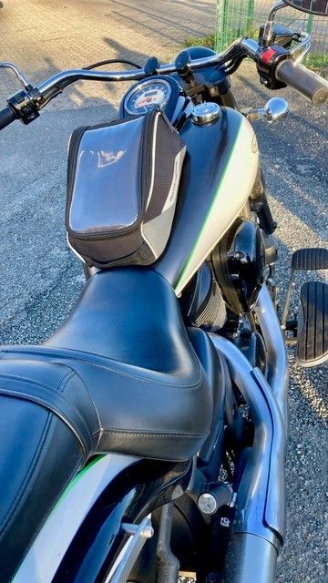 Motorrad mit schwarz-weißem Kraftstofftank, Tankrucksack und verchromten Auspuffrohren.