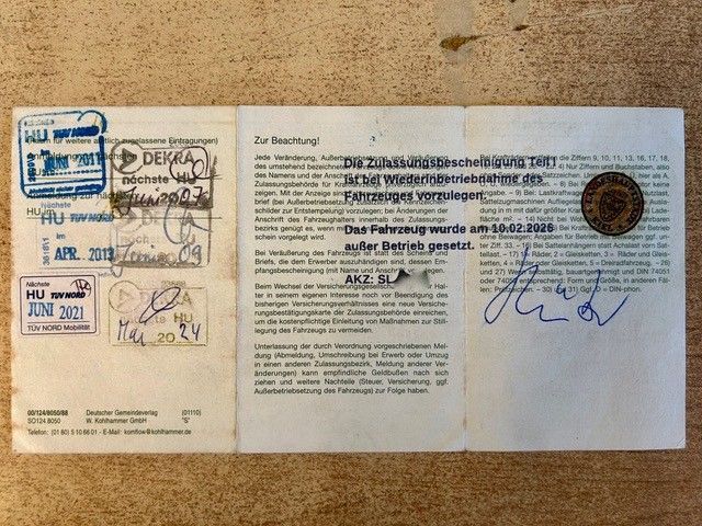 Passseite mit mehreren Stempeln, handschriftlichen Notizen und einer blauen Unterschrift auf beigem Hintergrund