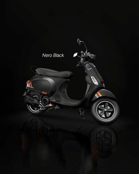 Schwarzer Vespa-Roller auf dunklem Hintergrund, Farbe Nero Black mit orangefarbenem Akzent.