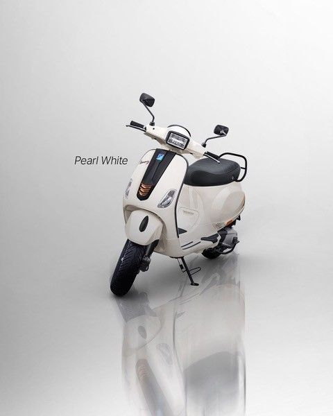 Perlweißer Vespa-Roller auf einer reflektierenden Oberfläche.