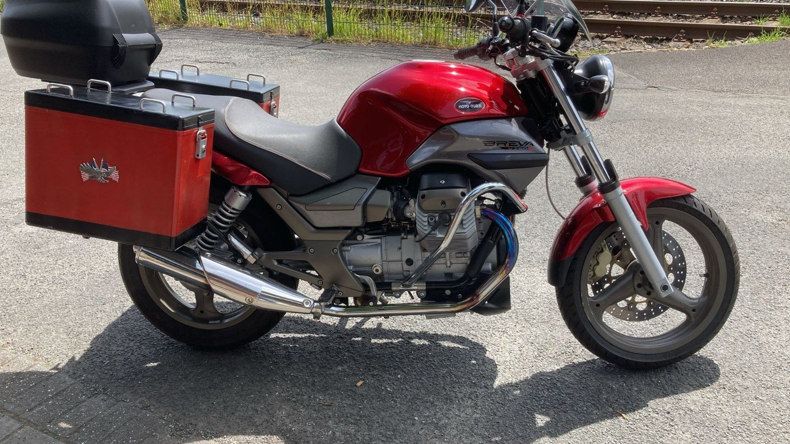 Ein rotes Motorrad ist am Straßenrand geparkt.