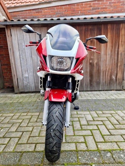 Rotes Motorrad auf Ziegelpflaster geparkt, Vorderansicht.