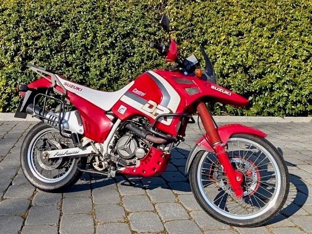 Ein rot-weißes Suzuki-Motorrad steht auf einer gemauerten Auffahrt