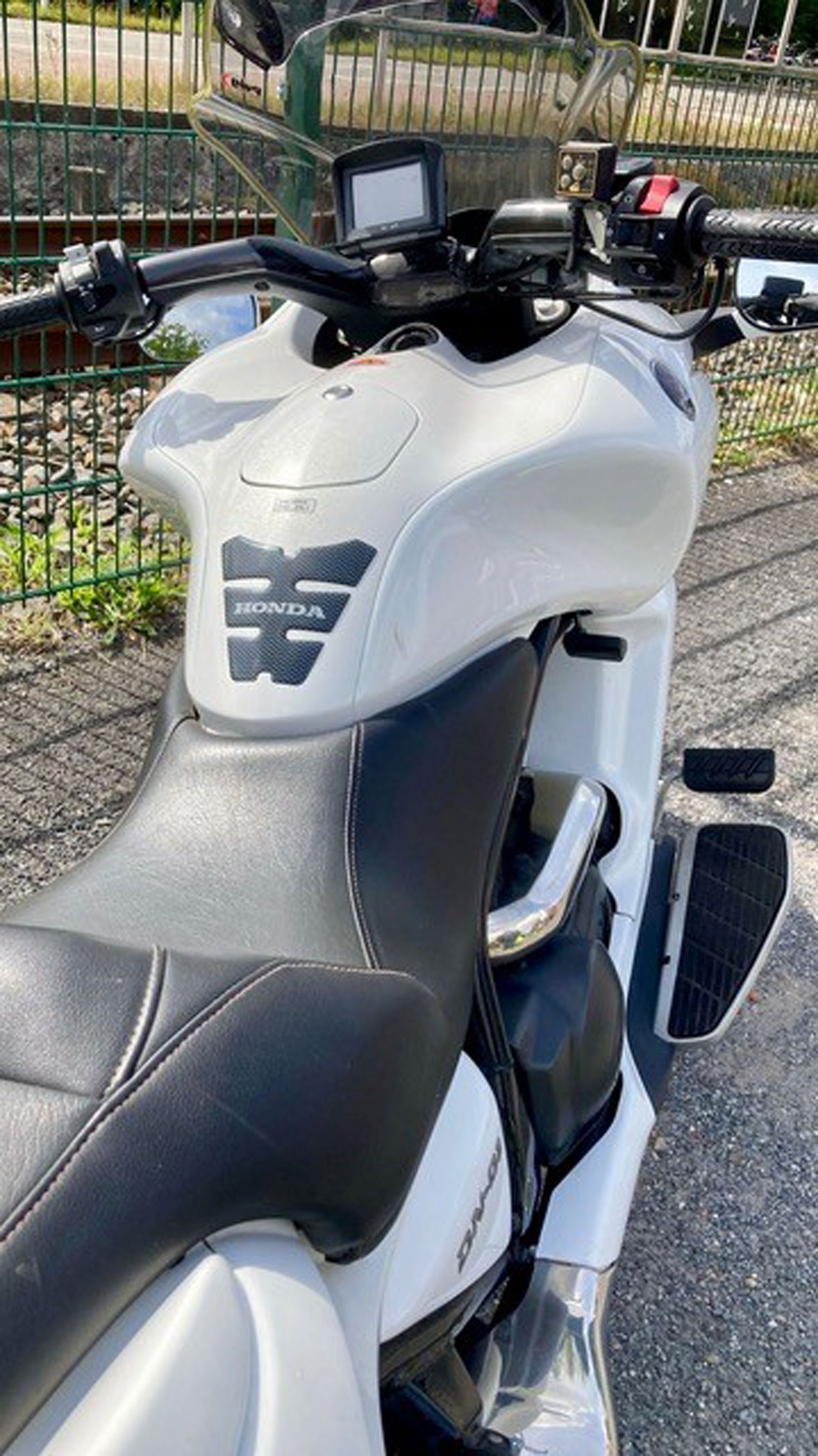 Weißes Motorrad mit schwarzem Sitz, draußen geparkt.